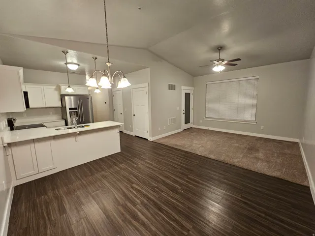 Kitchen featuring a peninsula, high end fridge, white cabinets, suspended lighting, and open floor plan
