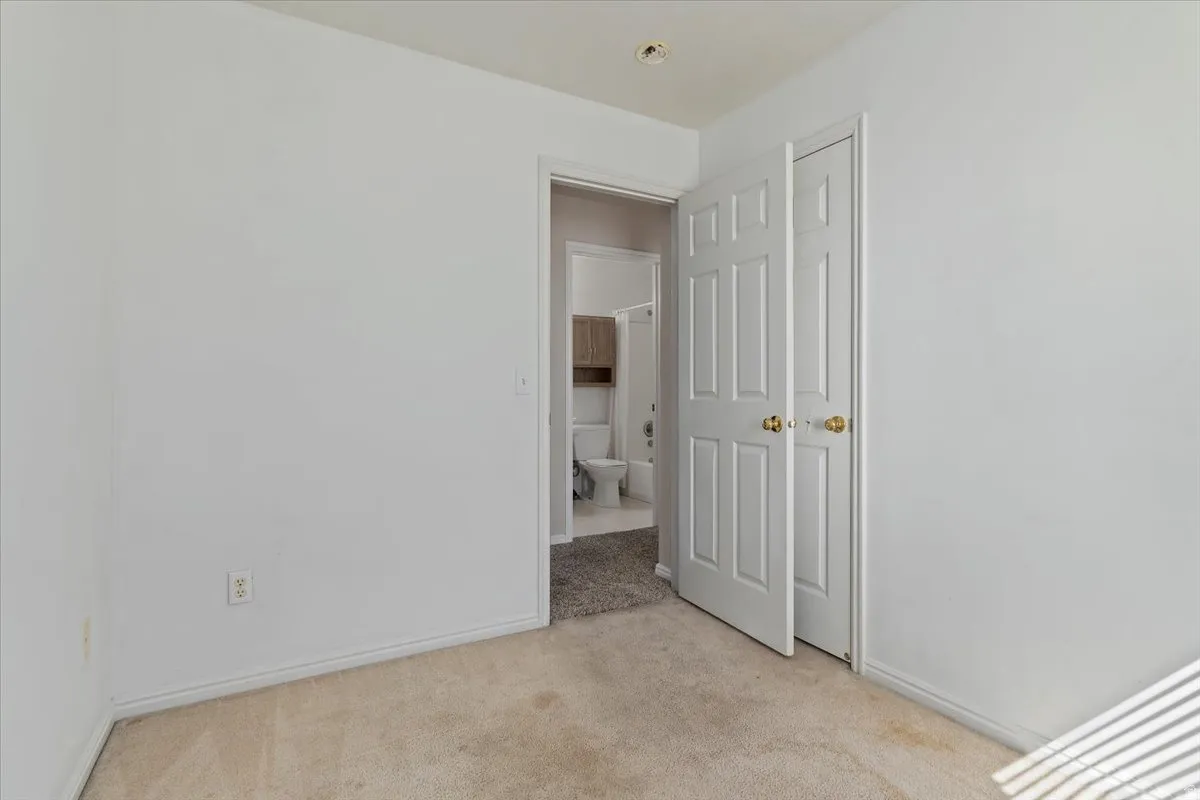 Unfurnished bedroom with baseboards and light colored carpet