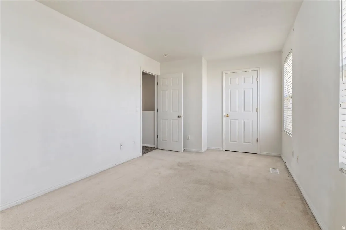 Unfurnished bedroom with light carpet and baseboards
