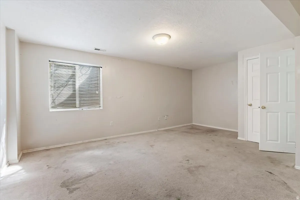 Unfurnished room featuring light carpet and a textured ceiling