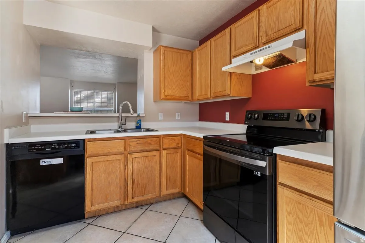Kitchen with range with electric stovetop, light countertops, dishwasher, and freestanding refrigerator