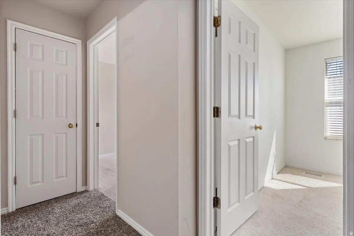 Hallway featuring light carpet and baseboards