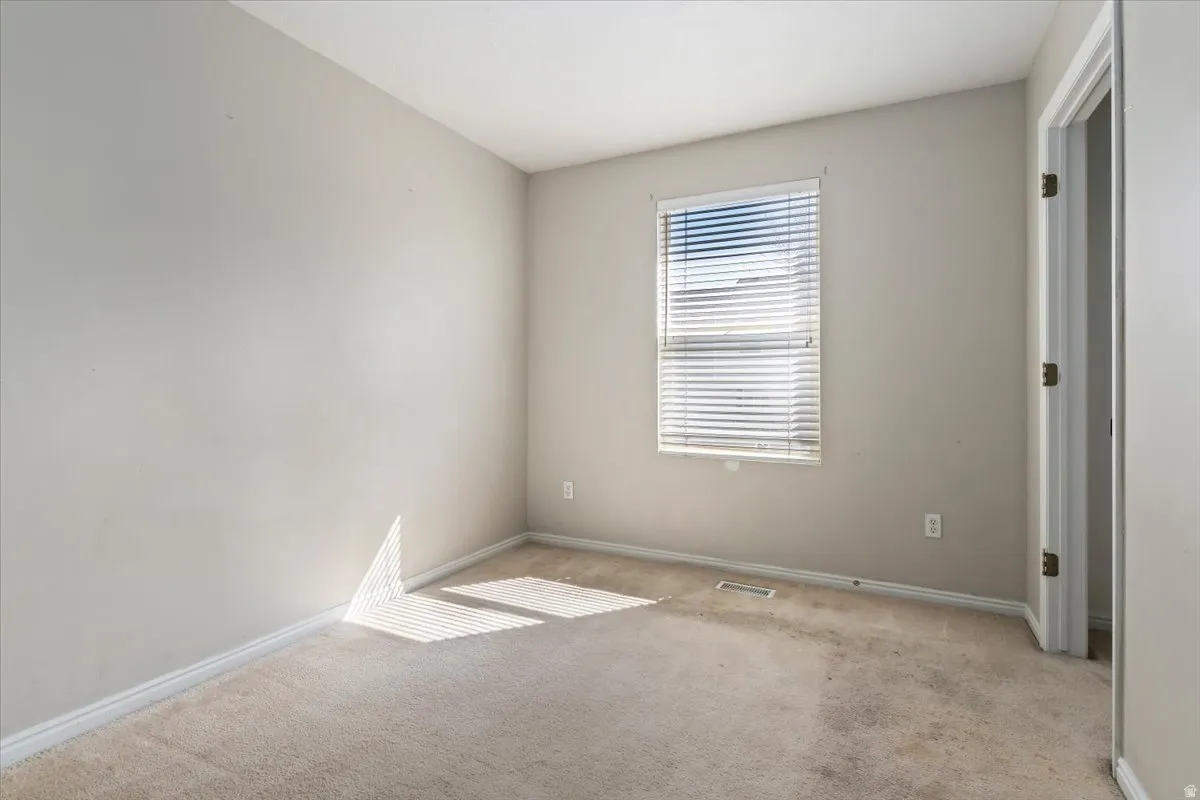 Unfurnished bedroom with light colored carpet and baseboards