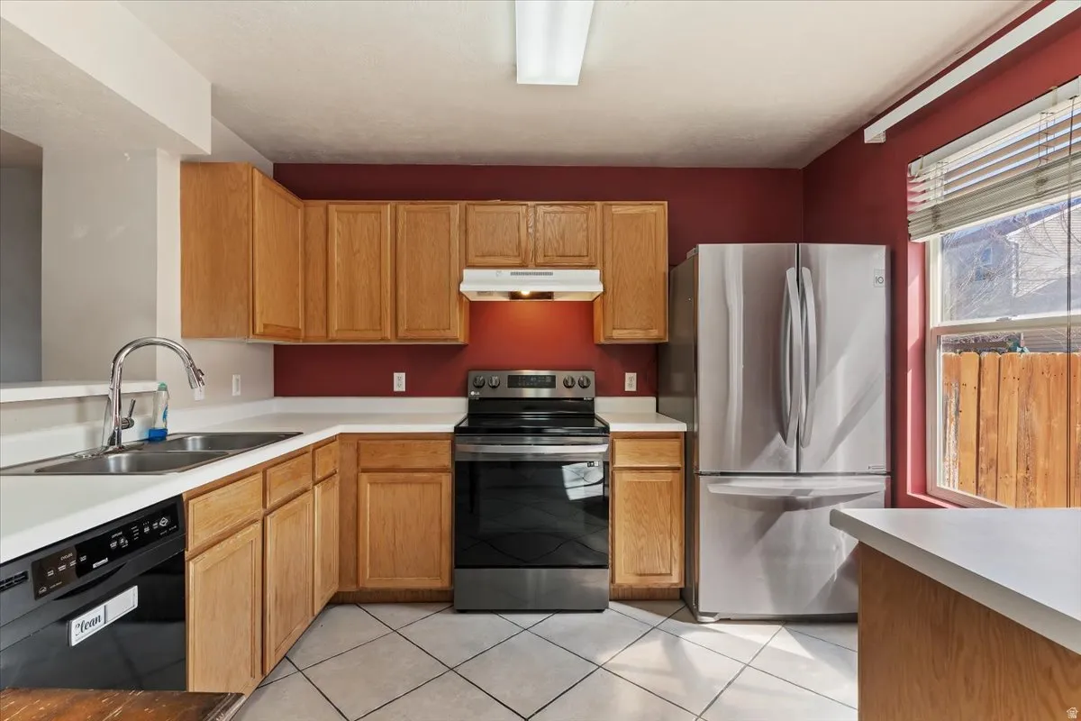 Kitchen with stainless steel appliances, light countertops, and light tile patterned flooring