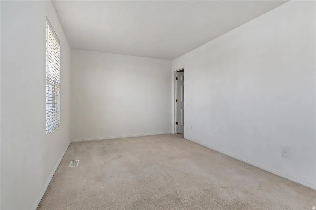 Spare room featuring light colored carpet and baseboards