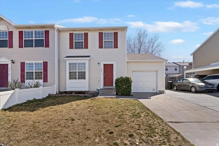 Twin house with driveway, a garage, a front yard, and entry steps