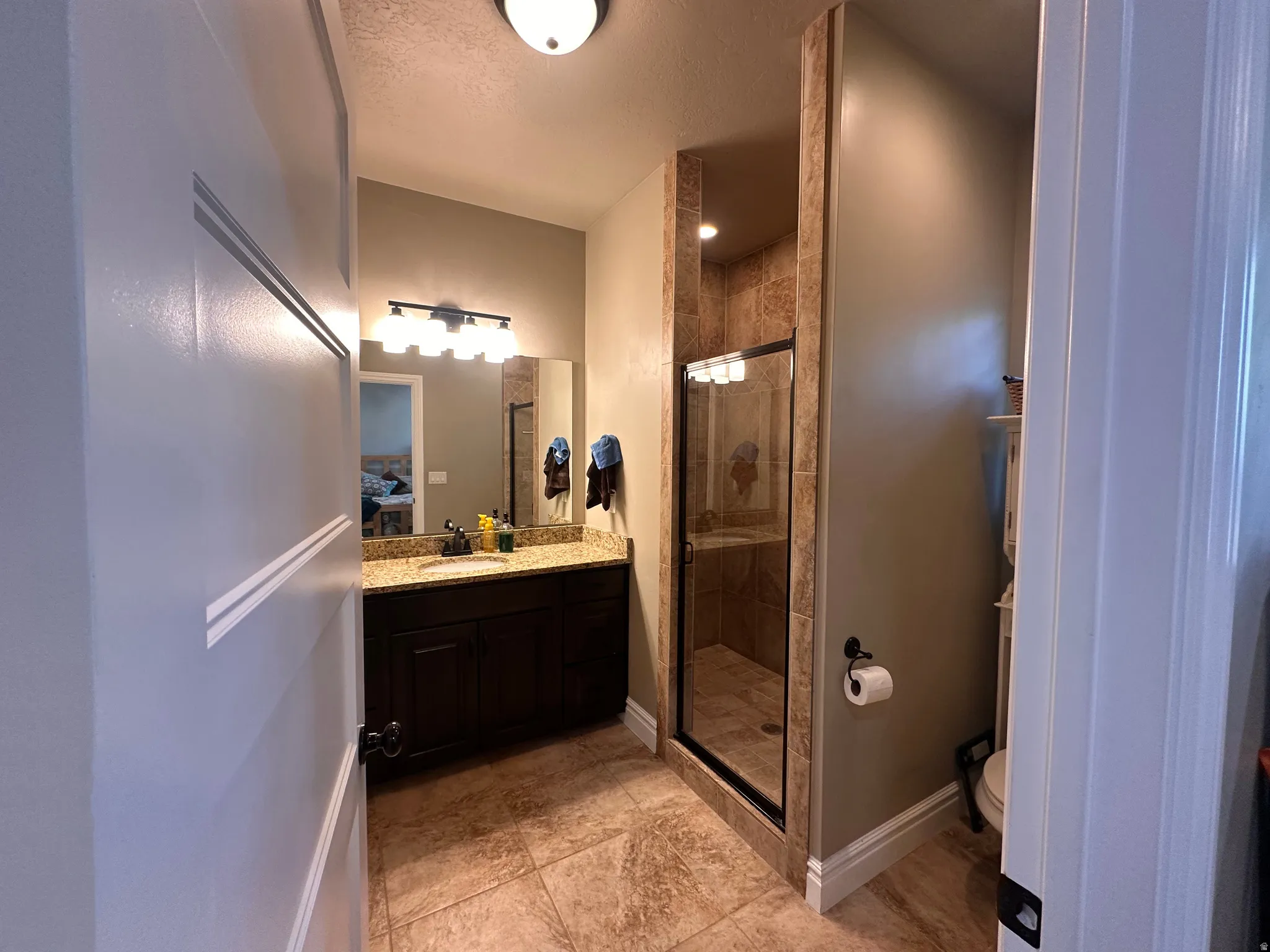Full bath featuring vanity, a shower stall, and a textured ceiling