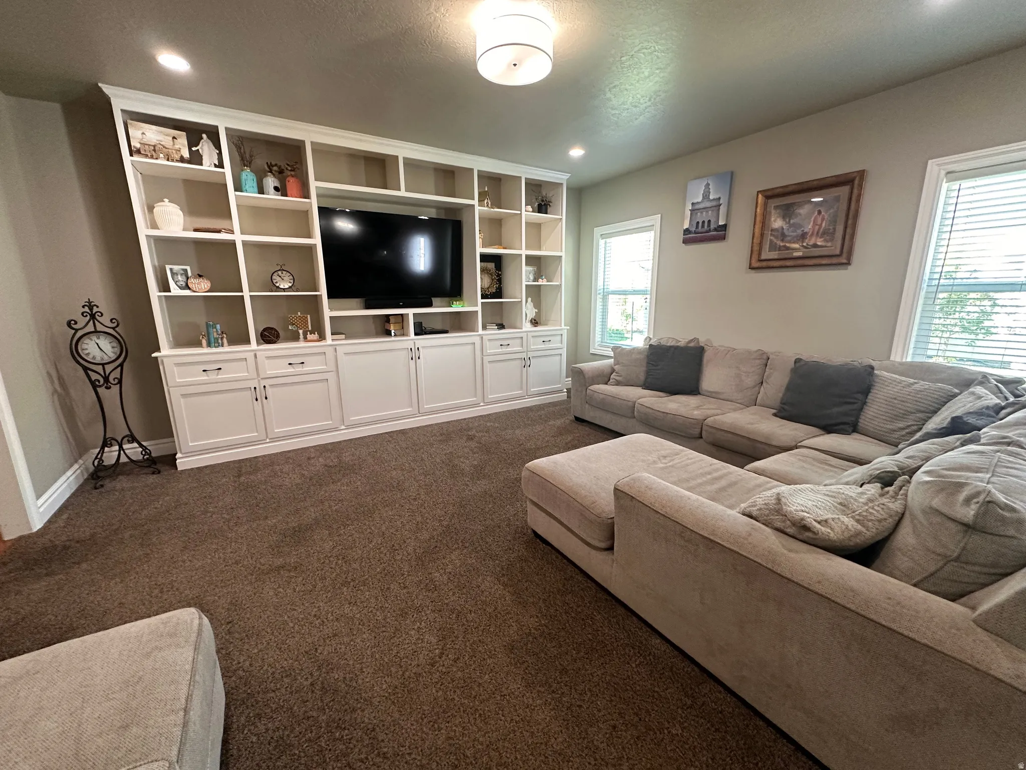 Living area featuring dark colored carpet and recessed lighting