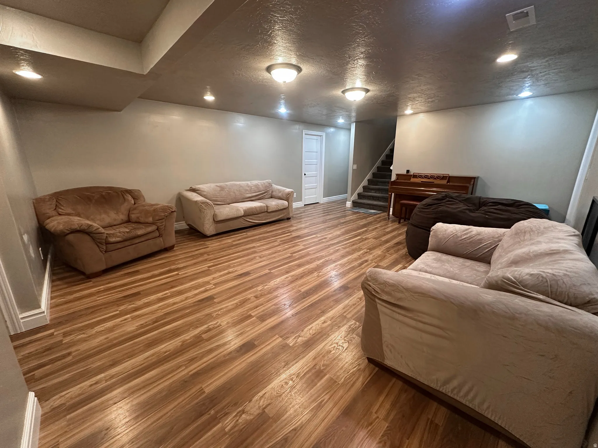 Living room with a textured ceiling, wood finished floors, and recessed lighting
