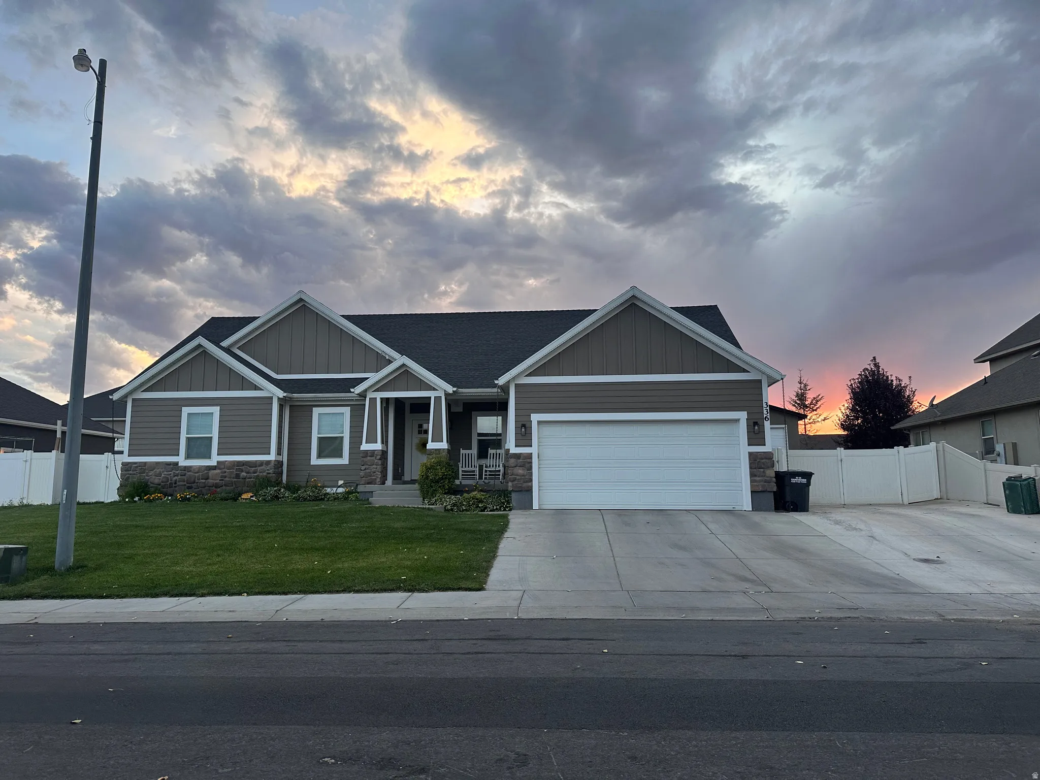 Craftsman inspired home featuring stone siding, board and batten siding, a garage, and driveway