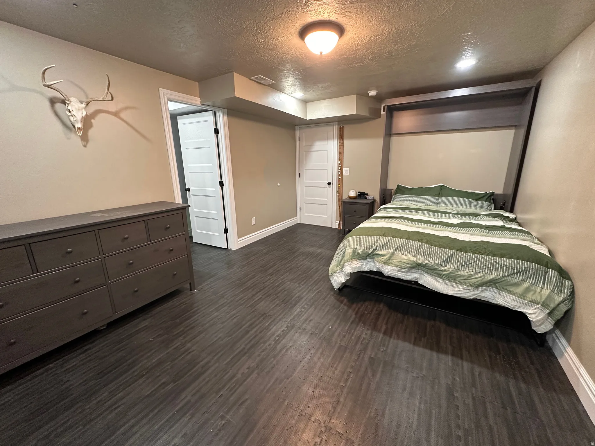 Bedroom with a textured ceiling and dark wood finished floors