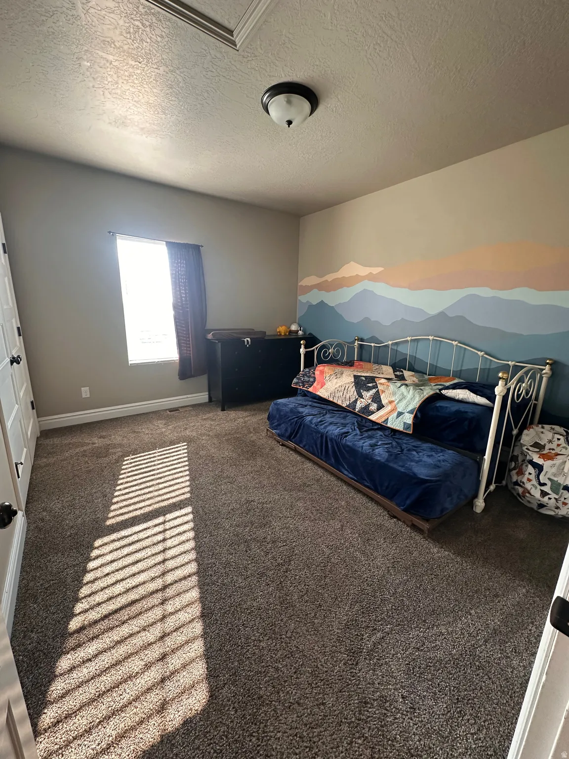 Carpeted bedroom featuring a textured ceiling and baseboards