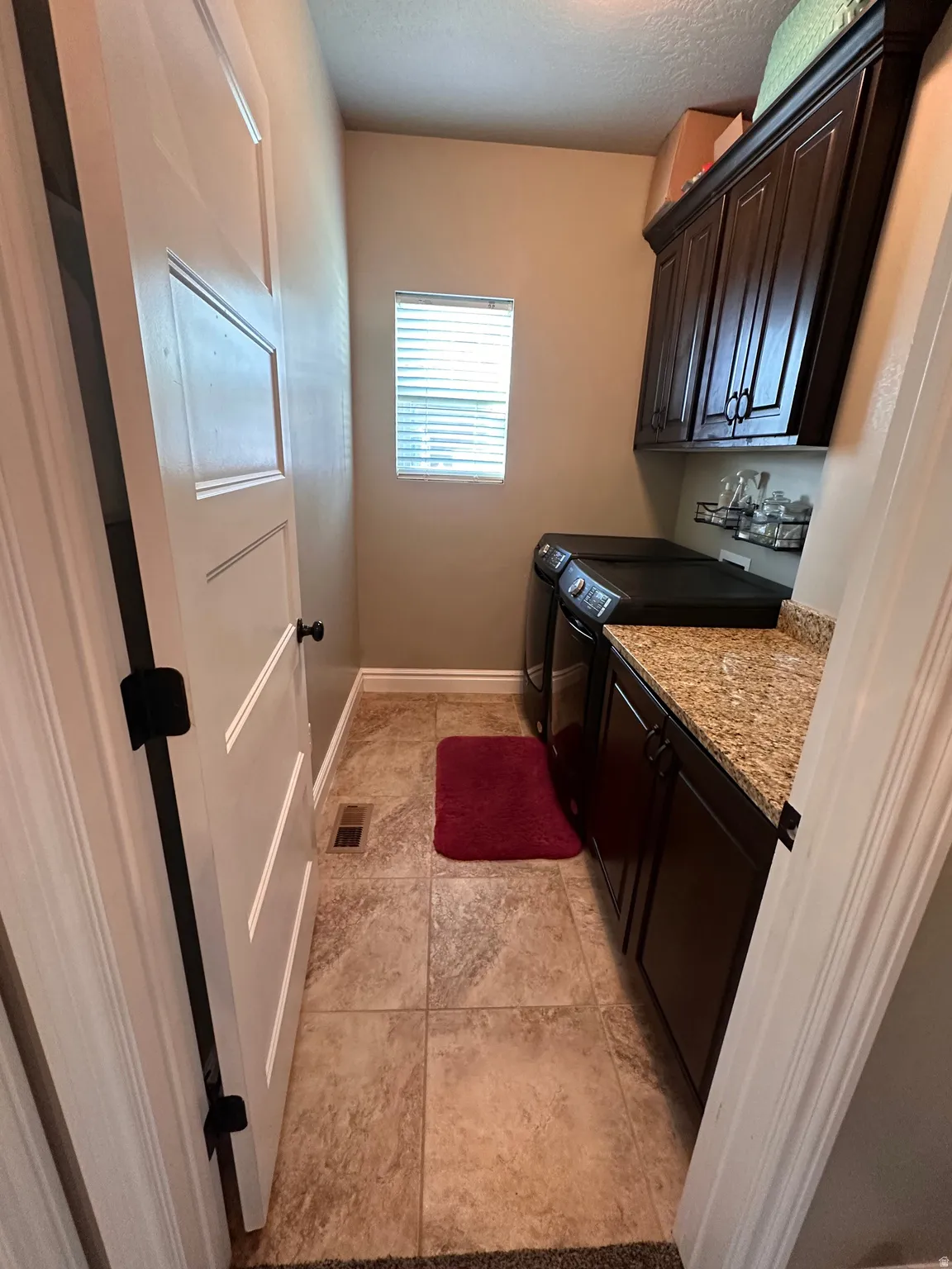 Laundry area featuring cabinet space, a textured ceiling, separate washer and dryer, and light tile patterned floors
