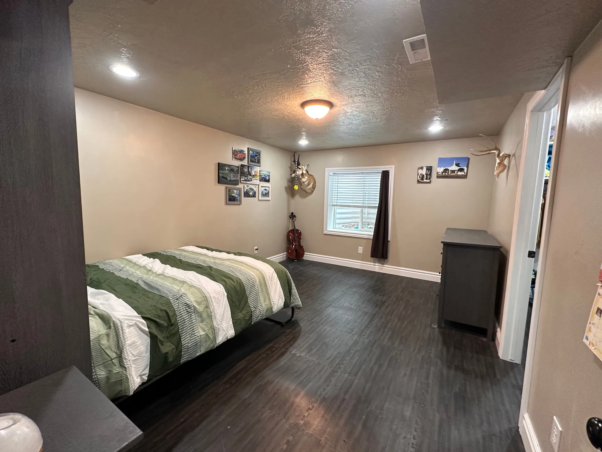 Bedroom with a textured ceiling and dark wood-style flooring