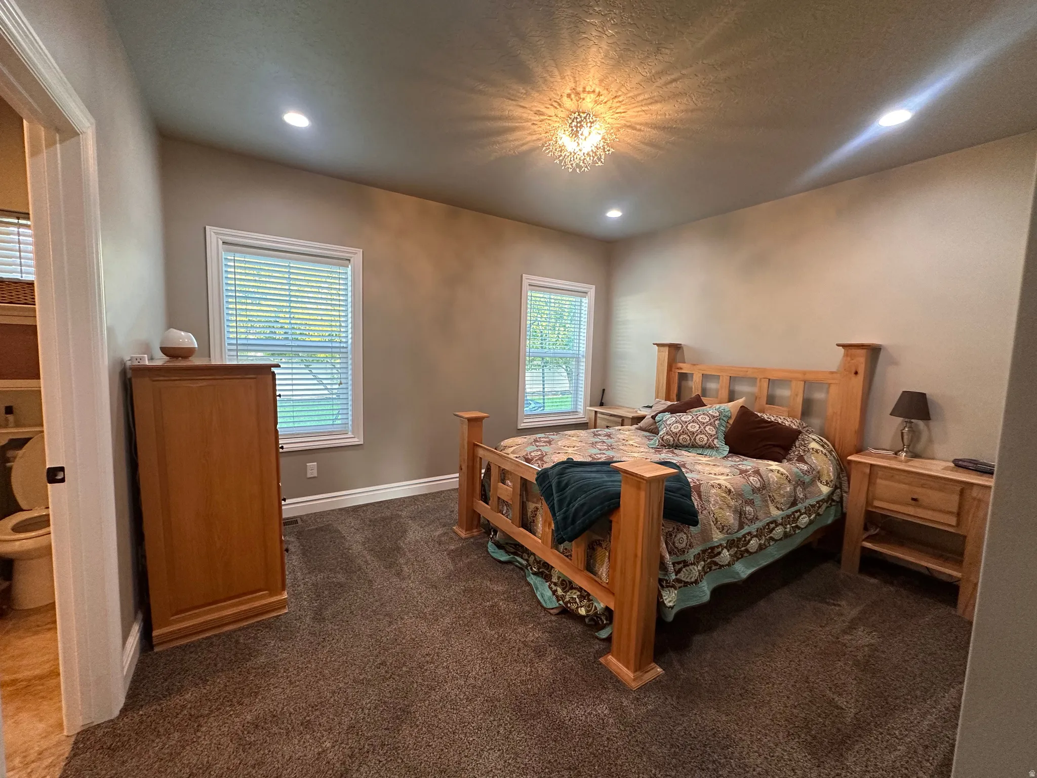 Bedroom with dark colored carpet, ensuite bath, and recessed lighting