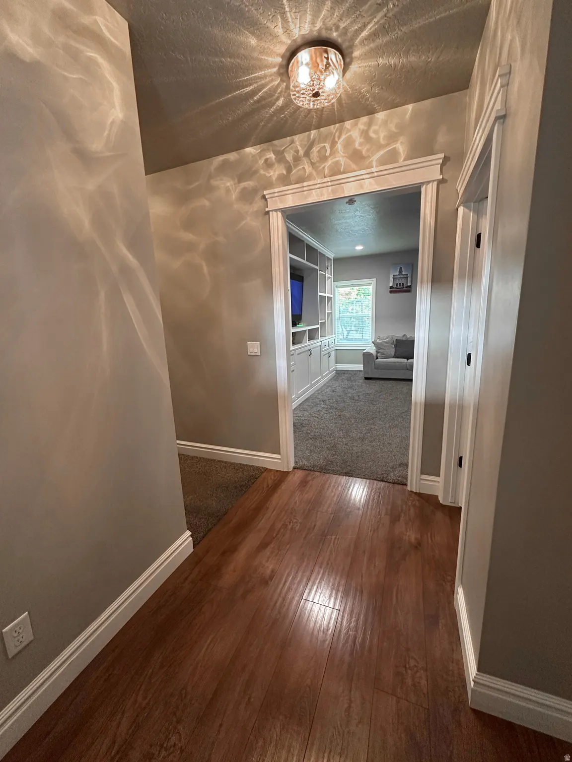 Hallway with dark wood-style floors, built in features, and a textured ceiling
