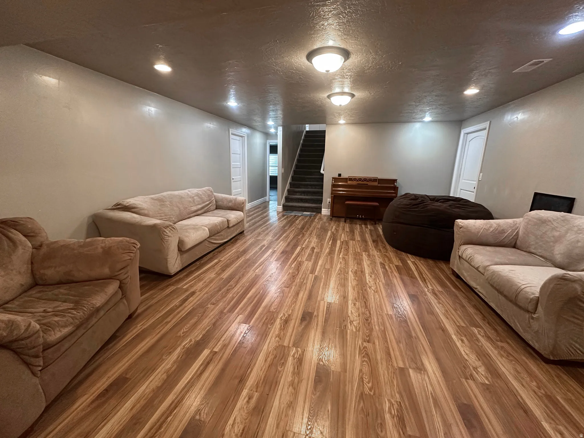 Living room featuring a textured ceiling, wood finished floors, and recessed lighting