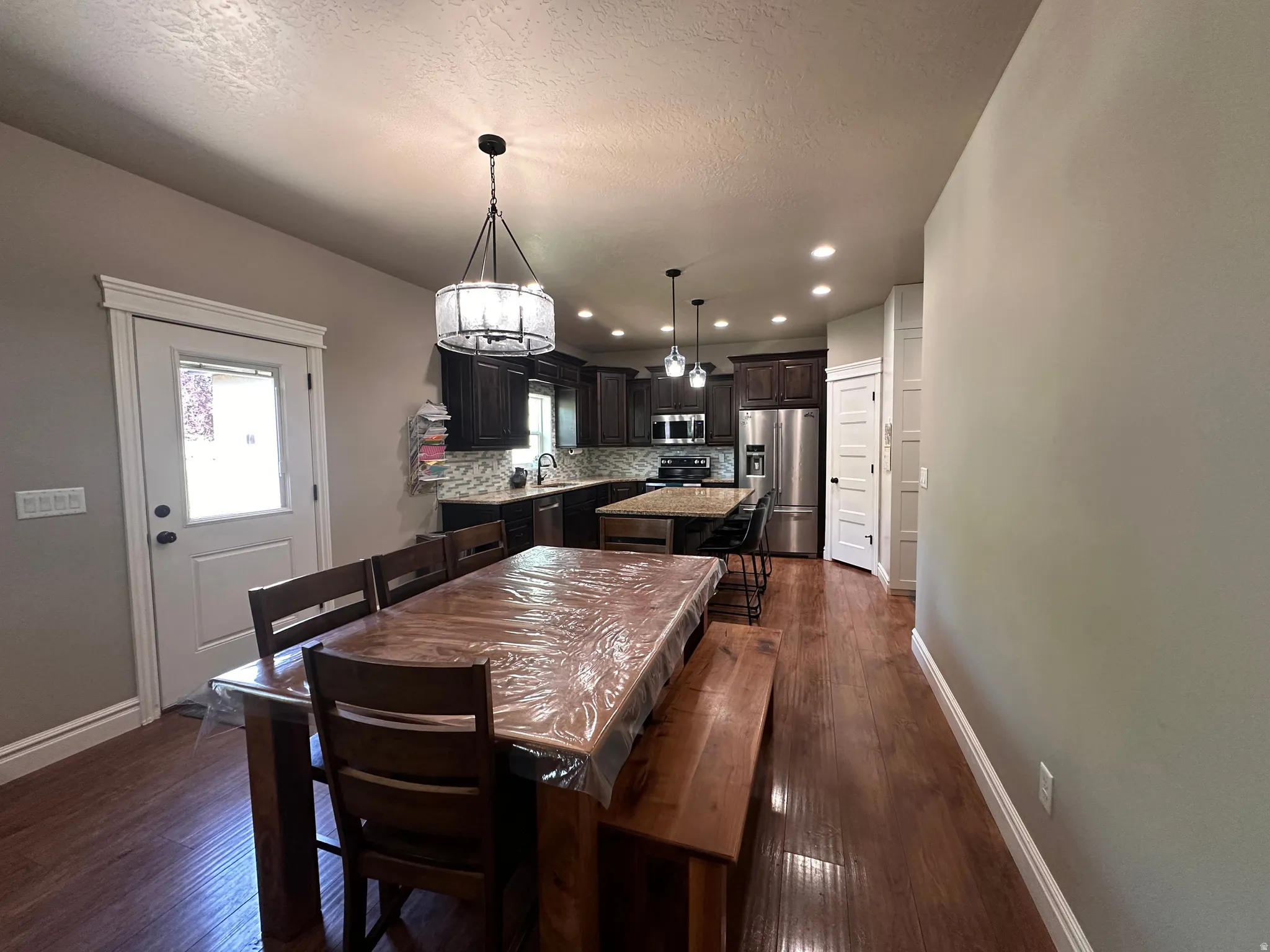 Dining space with dark wood finished floors, recessed lighting, and a textured ceiling