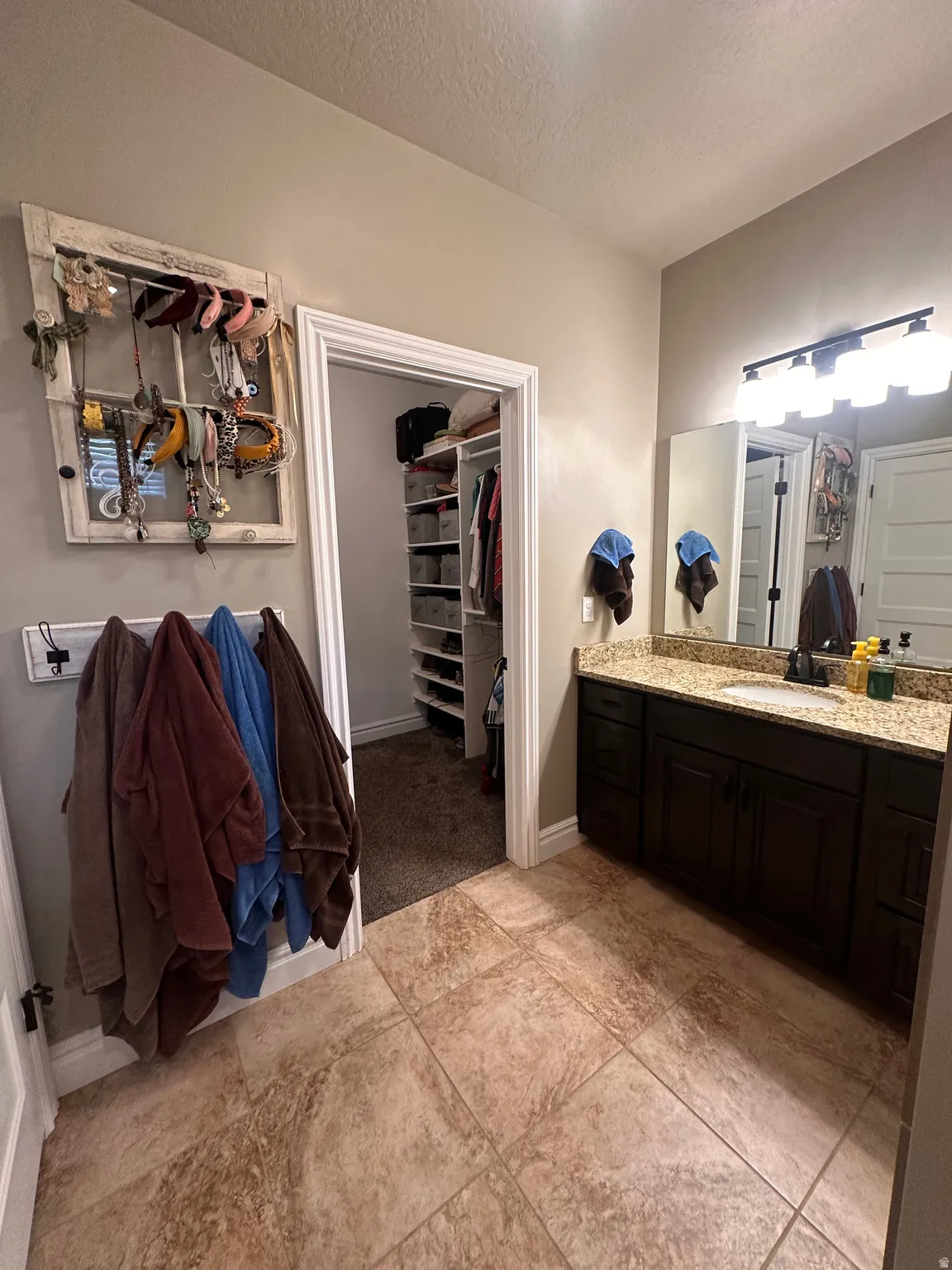 Bathroom with vanity, a spacious closet, and a textured ceiling