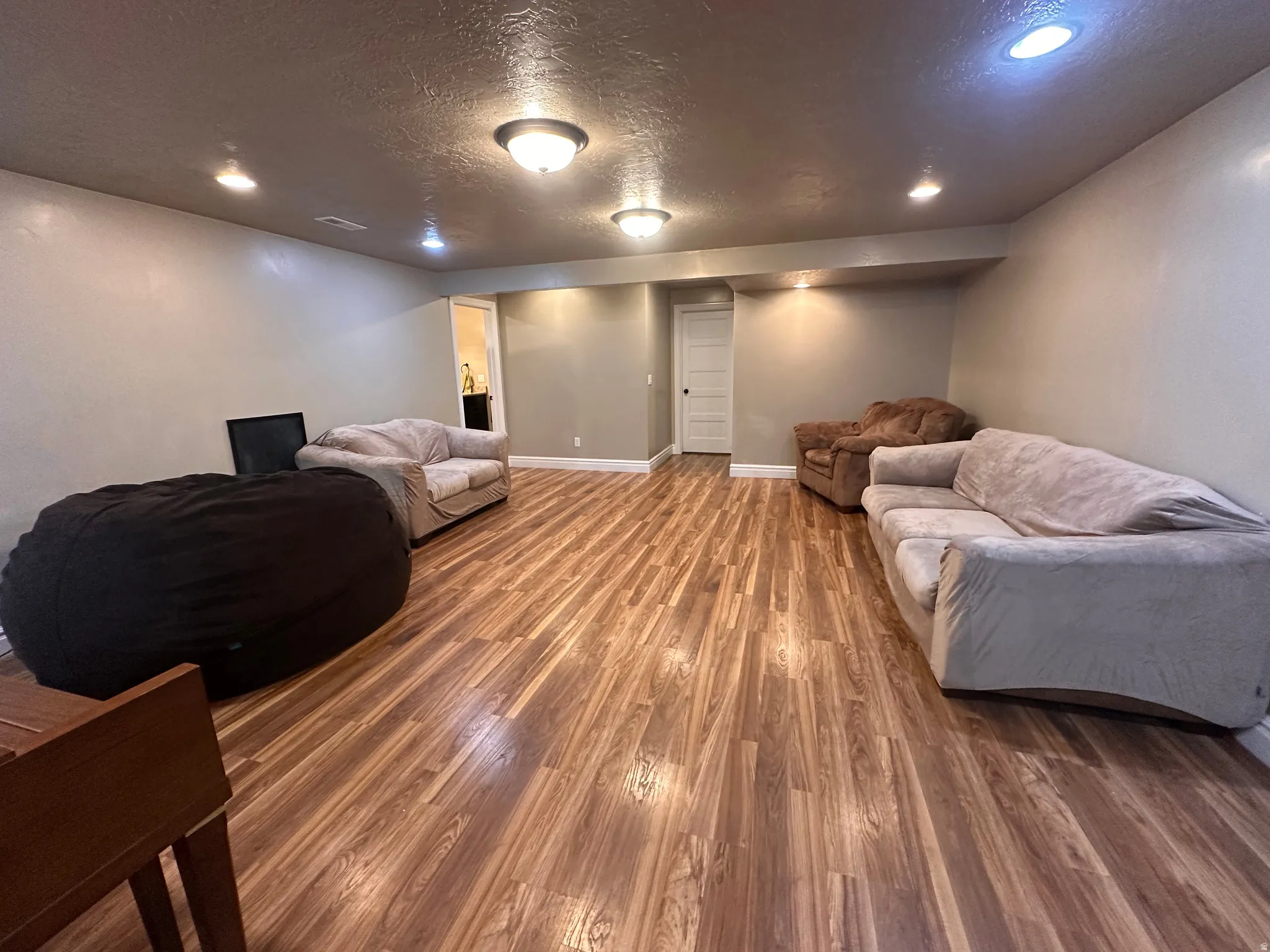Living area featuring wood finished floors, a textured ceiling, and recessed lighting