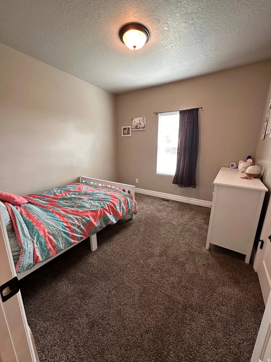 Bedroom featuring dark colored carpet and a textured ceiling