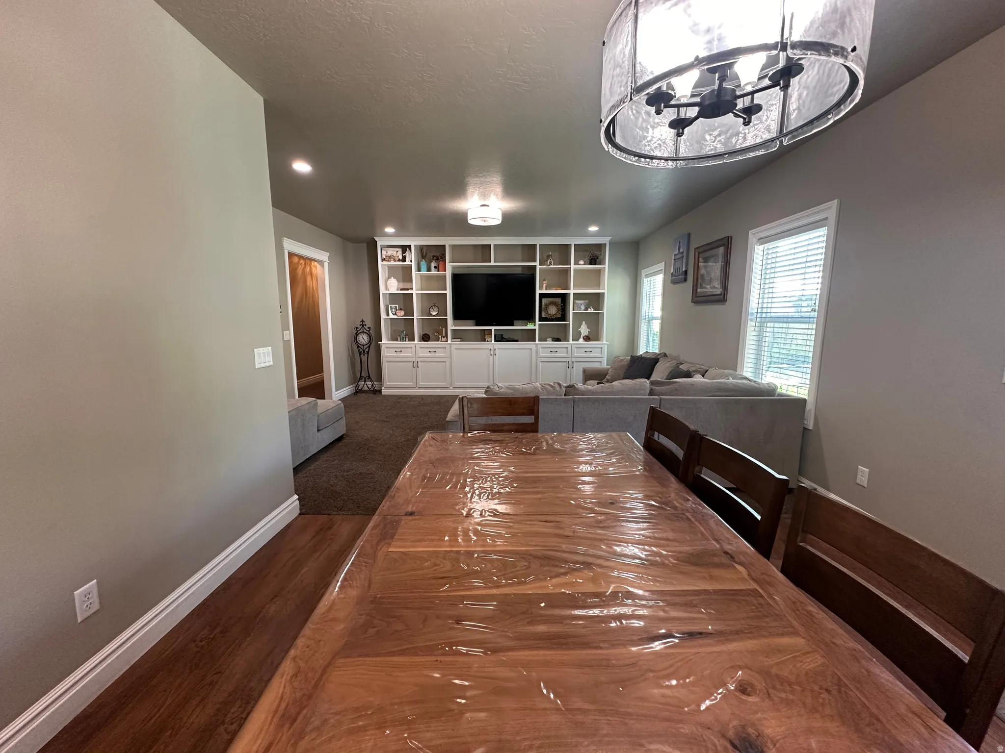 Dining space featuring dark wood-style floors, suspended lighting, and a textured ceiling