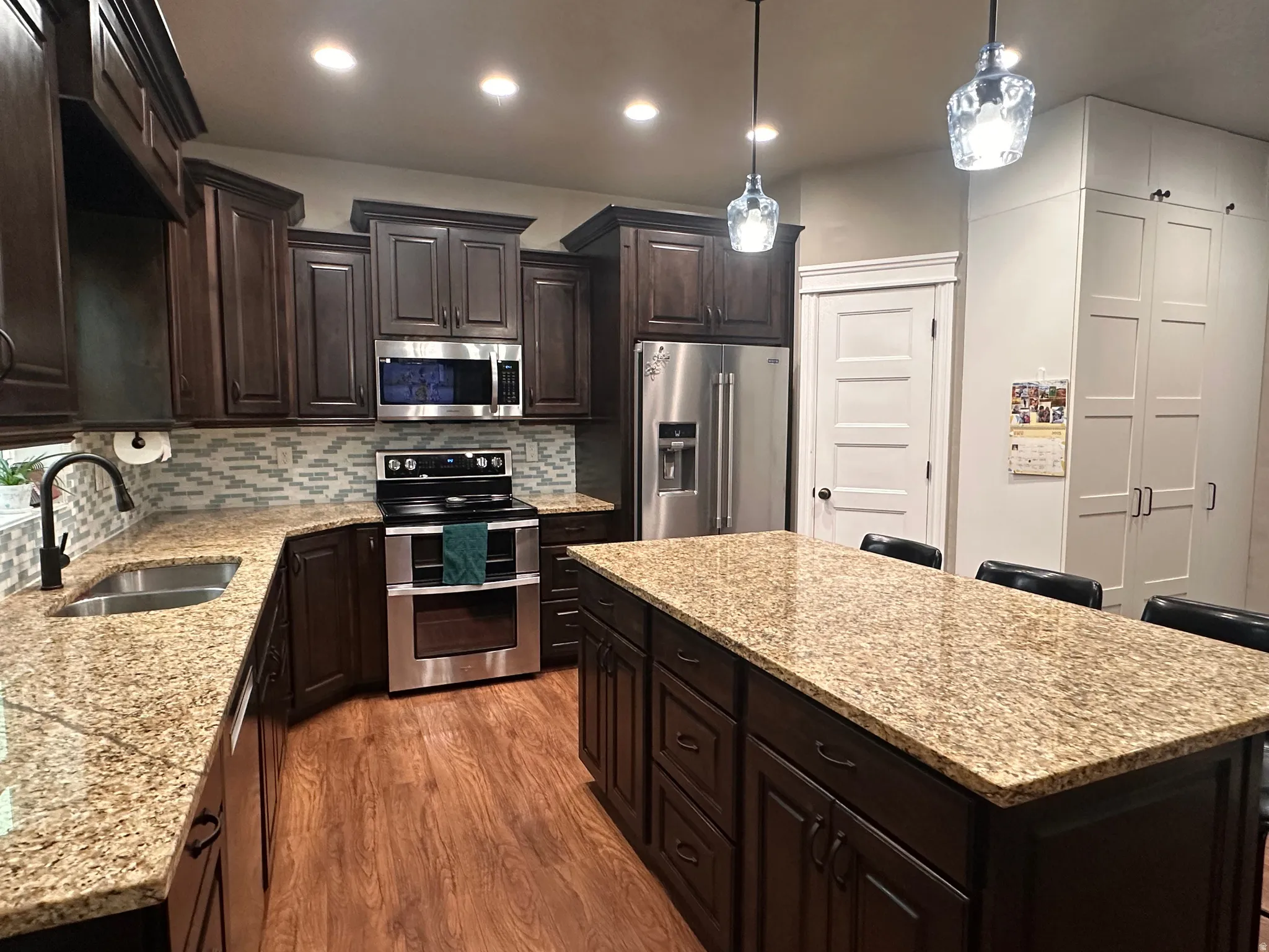 Kitchen with dark wood finish cabinets, stainless steel appliances, a center island, a breakfast bar area, and light stone counters