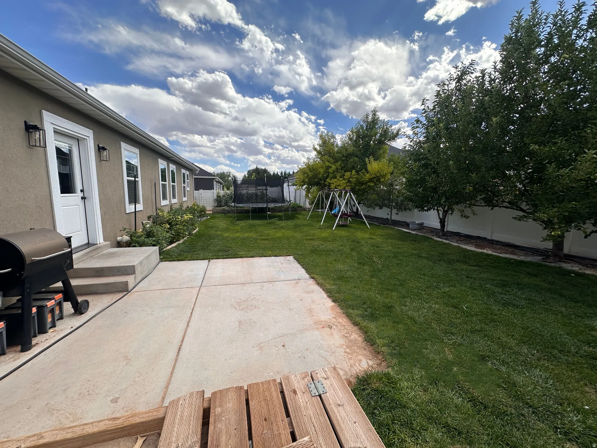 Fenced backyard featuring a patio, a trampoline, and a playground