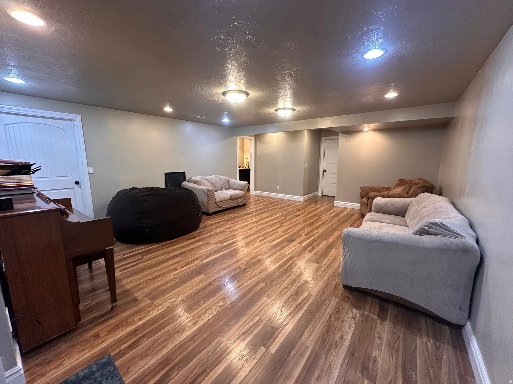 Living area with a textured ceiling, recessed lighting, and dark wood-type flooring