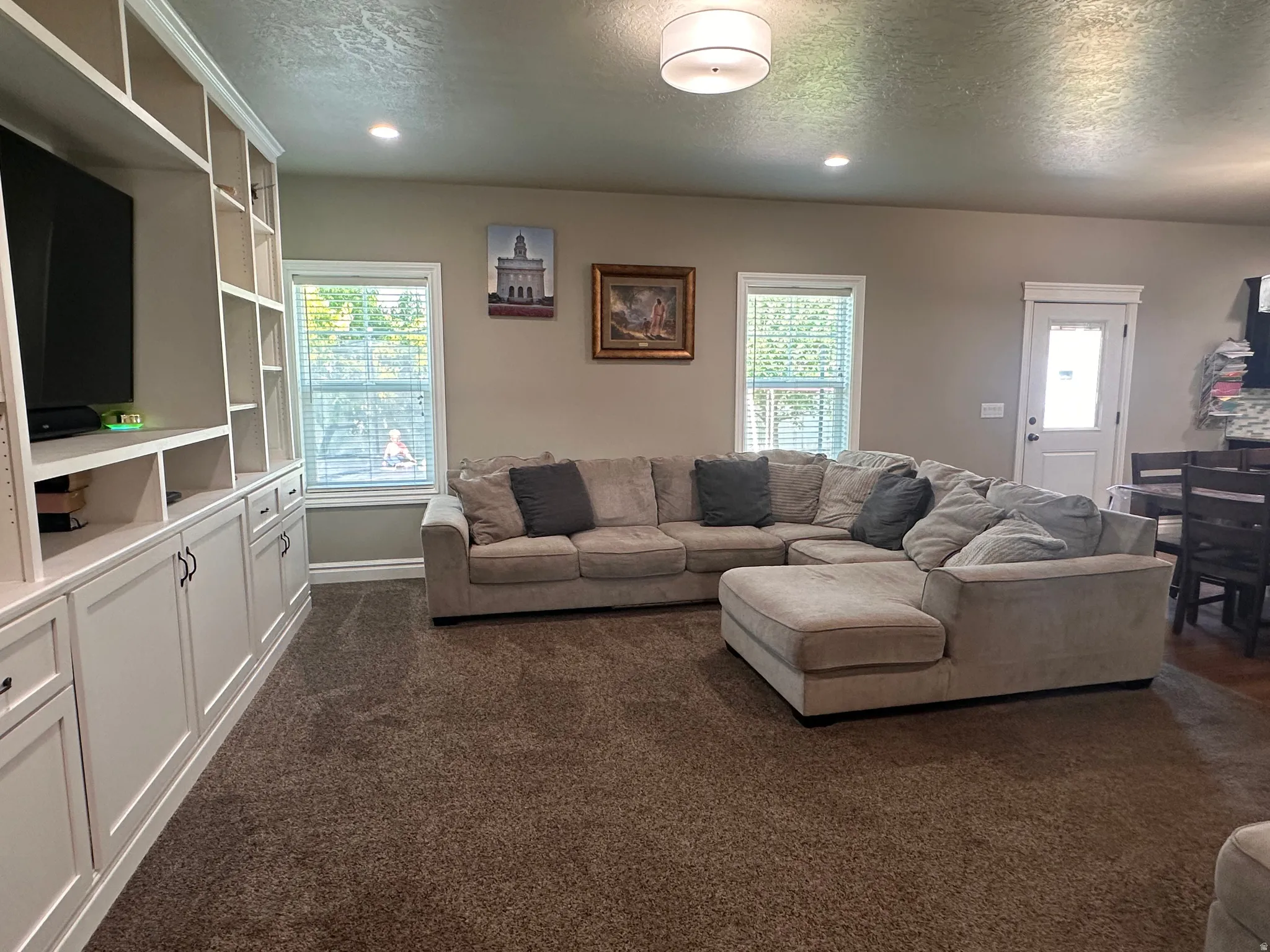 Living room with dark carpet, a textured ceiling, and recessed lighting