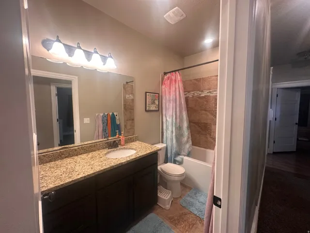 Full bathroom featuring vanity, shower / bath combo with shower curtain, and light tile patterned floors