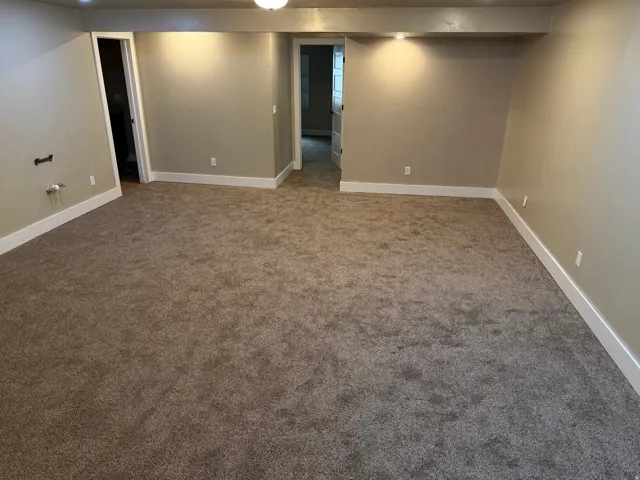 Spacious room featuring plush carpeting and neutral tone walls with white baseboards