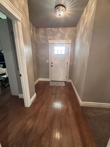 Doorway with wood-type flooring and baseboards