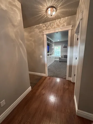 Hallway with dark wood-style floors, built in features, and a textured ceiling