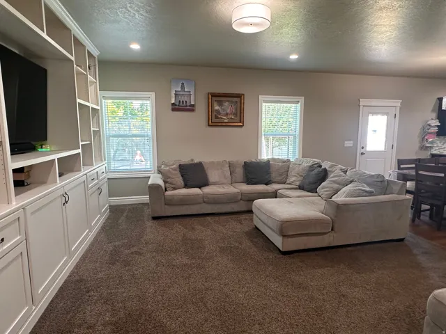 Living room with dark carpet, a textured ceiling, and recessed lighting