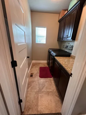 Laundry area featuring cabinet space, a textured ceiling, separate washer and dryer, and light tile patterned floors
