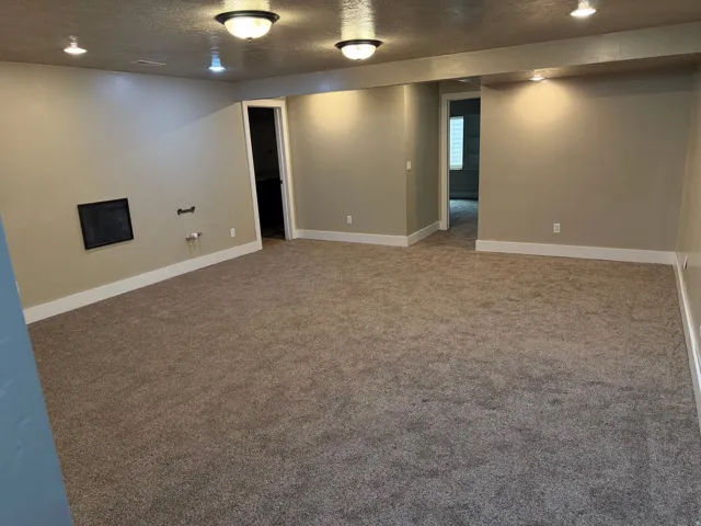 Expansive carpeted area featuring light beige walls and white baseboards