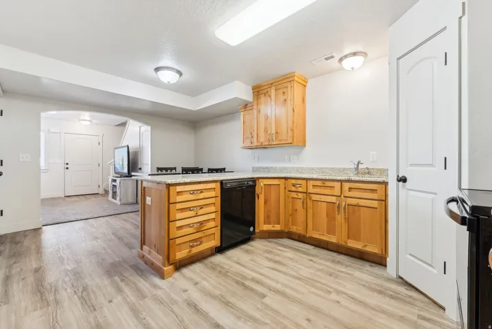 Kitchen featuring a peninsula, arched walkways, light wood-type flooring, and dishwasher