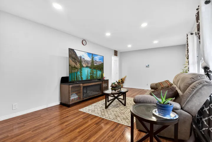 Living room with wood finished floors, recessed lighting, and a glass covered fireplace