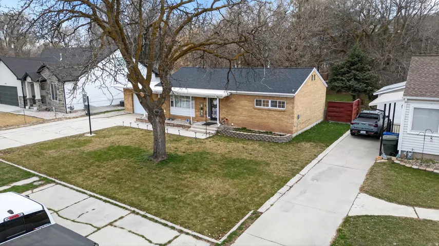 Ranch-style house featuring concrete driveway, brick siding, a front yard, and roof with shingles