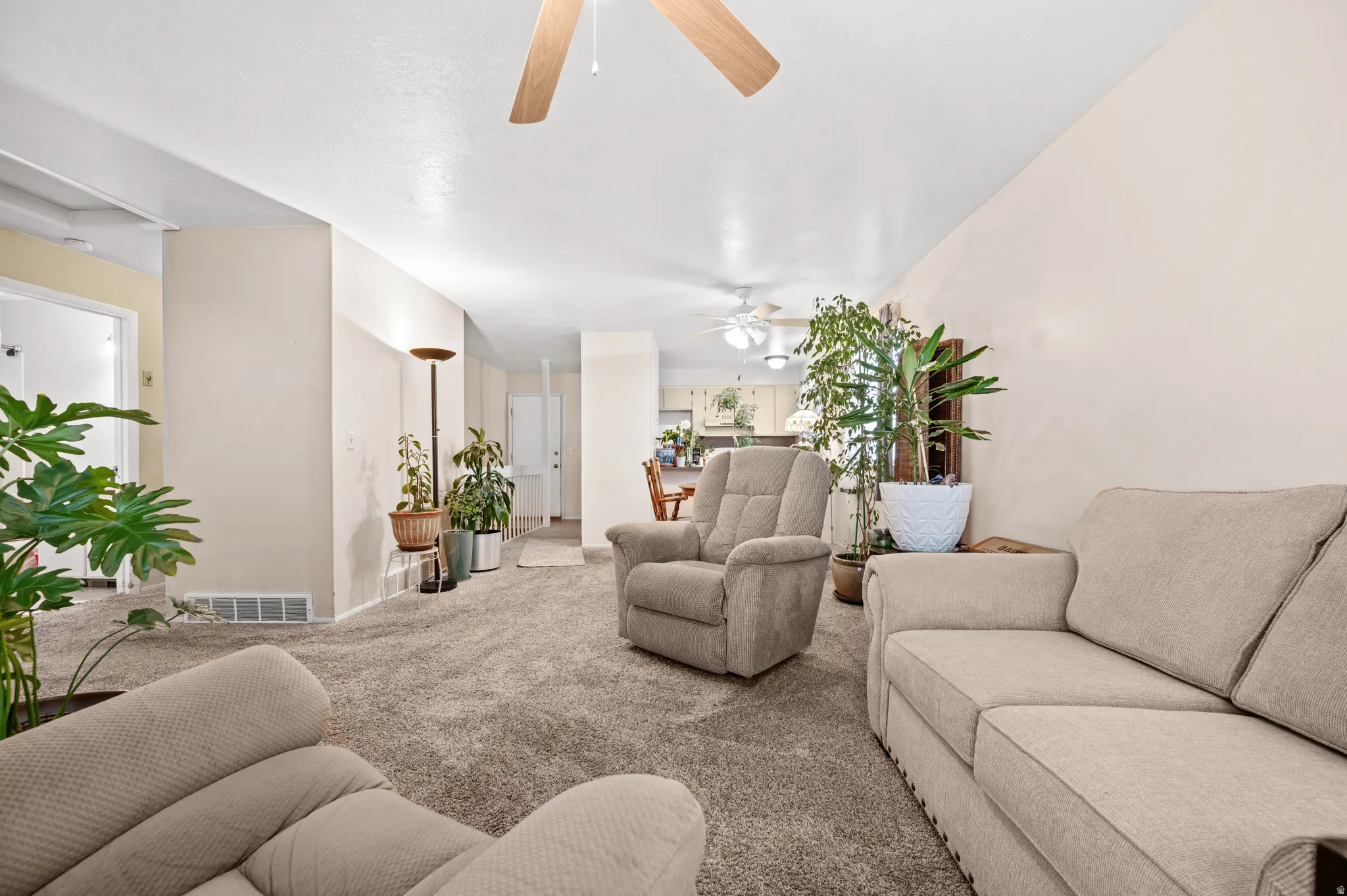 Carpeted living room with a ceiling fan