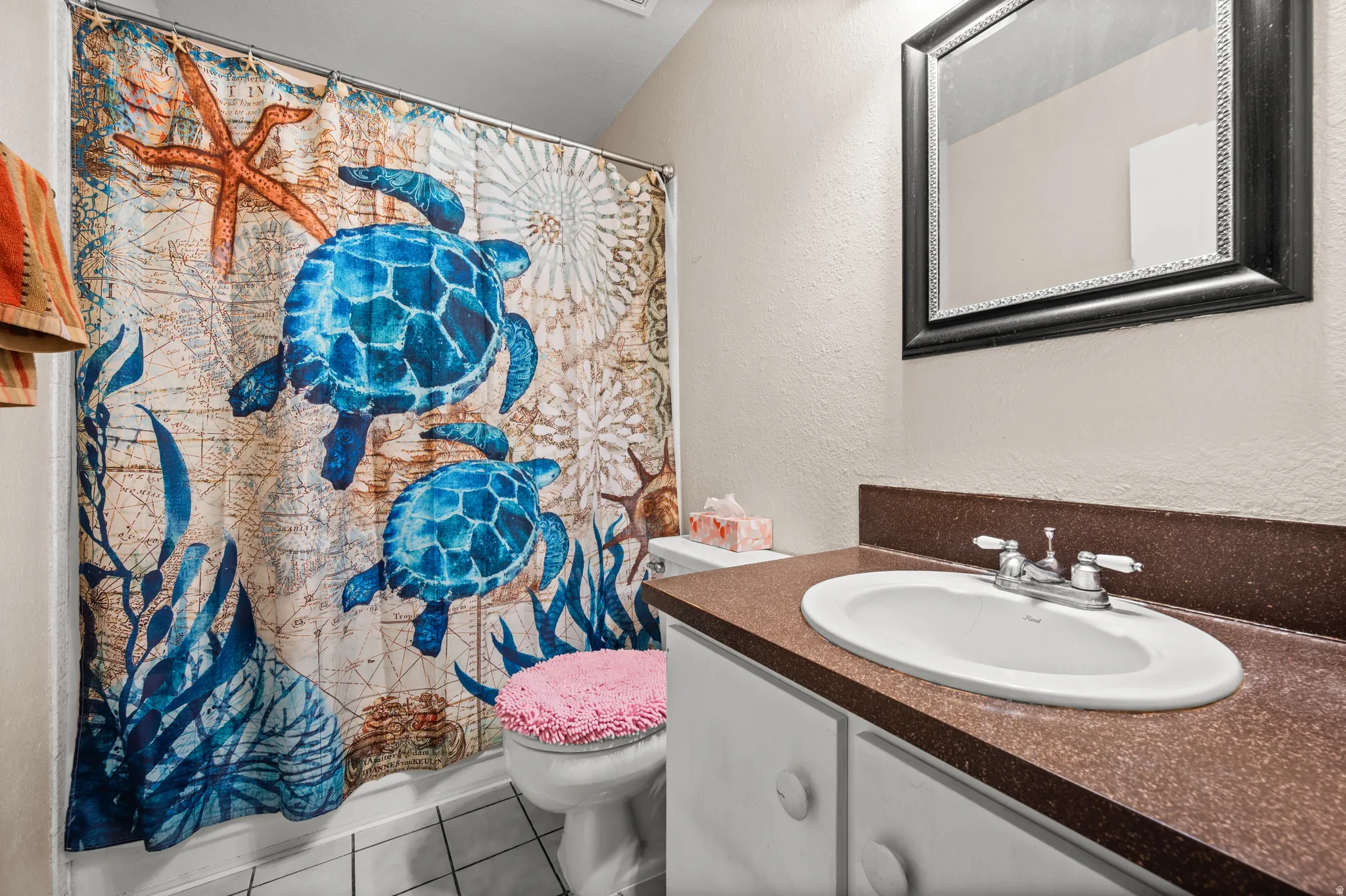 Bathroom with a textured wall, a shower with curtain, vanity, and tile patterned flooring
