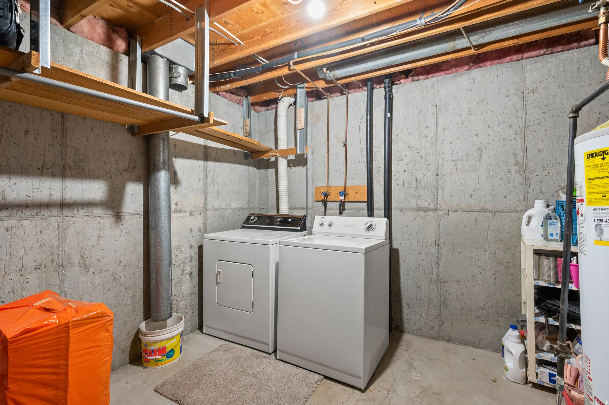 Laundry area featuring concrete floors, washer and clothes dryer, and water heater