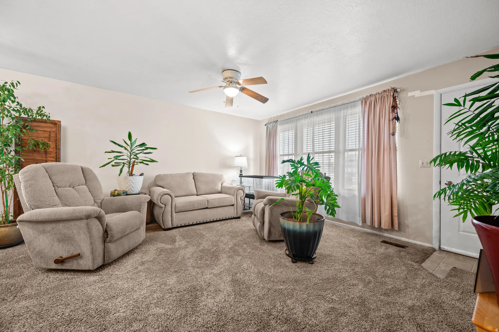 Carpeted living area with a ceiling fan
