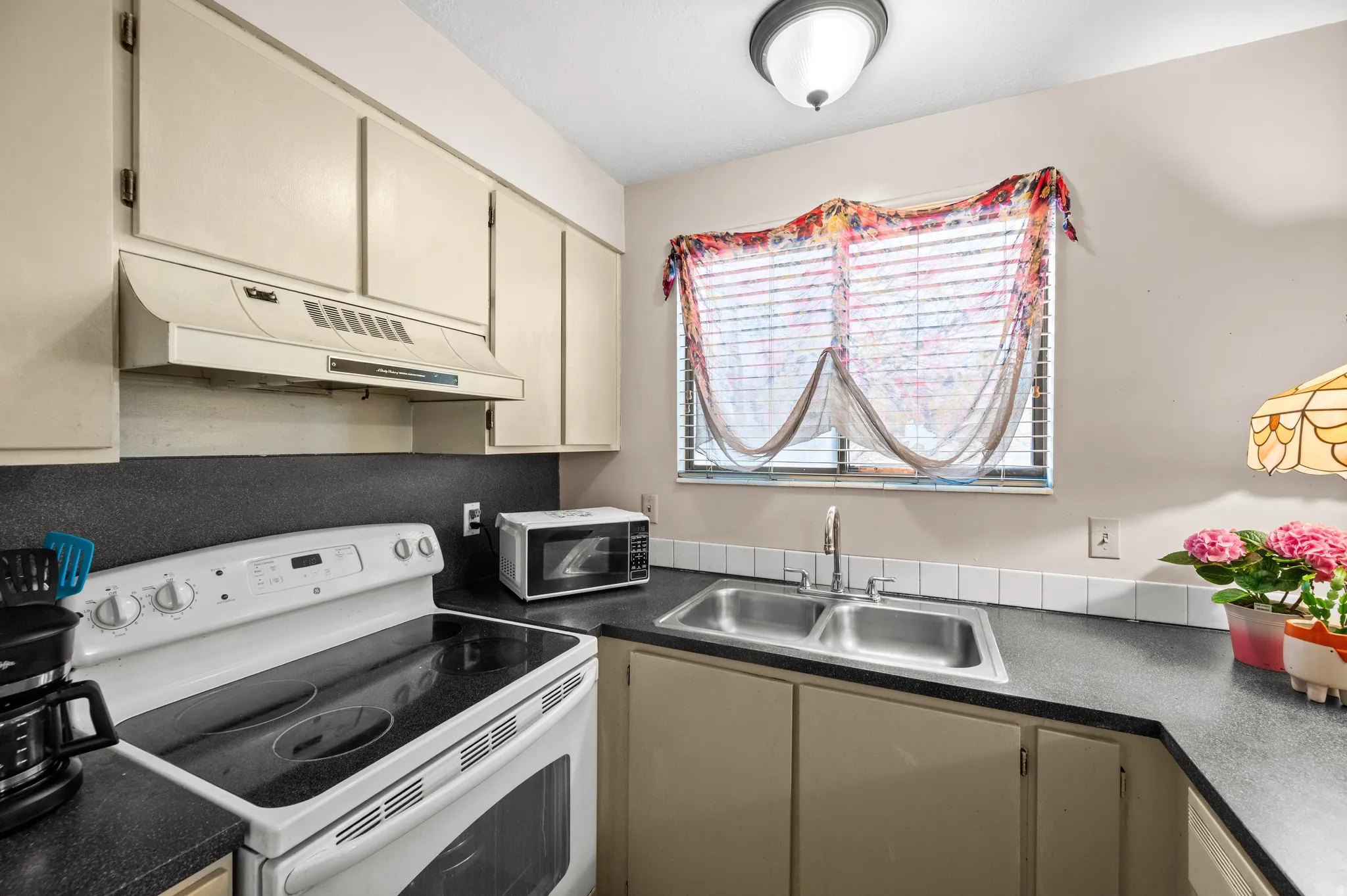 Kitchen featuring electric range, dark countertops, and cream cabinets