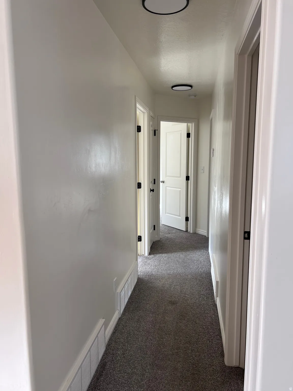 Hall with dark carpet and baseboards