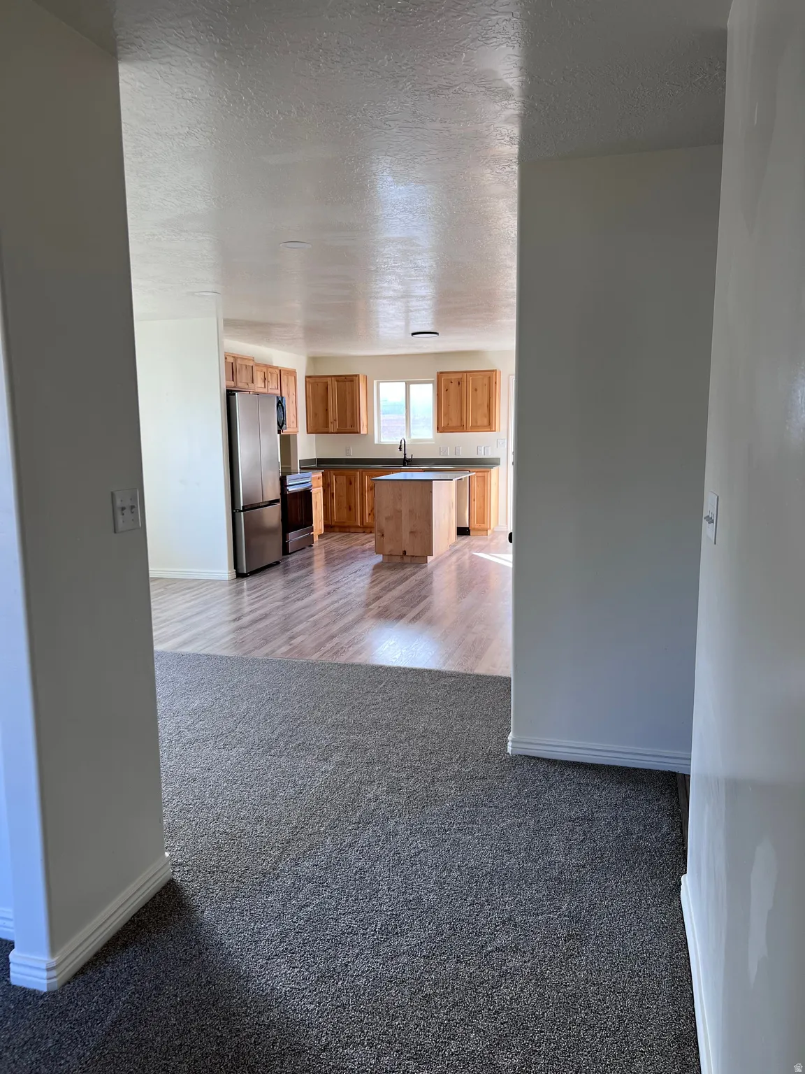 Unfurnished living room featuring dark colored carpet and a textured ceiling