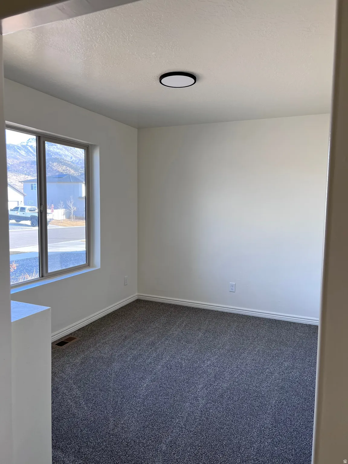 Unfurnished room featuring dark carpet and a textured ceiling