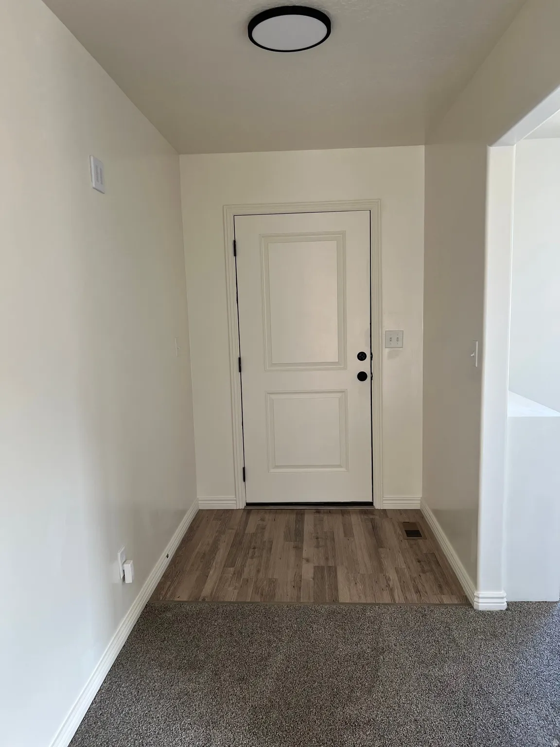Doorway featuring carpet floors and baseboards