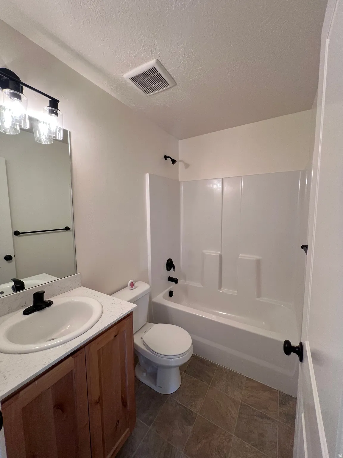 Full bath with vanity, a textured ceiling, and shower / bathtub combination
